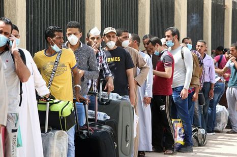 مجموعة من الأشخاص ينتظرون في طابور مع حقائب.