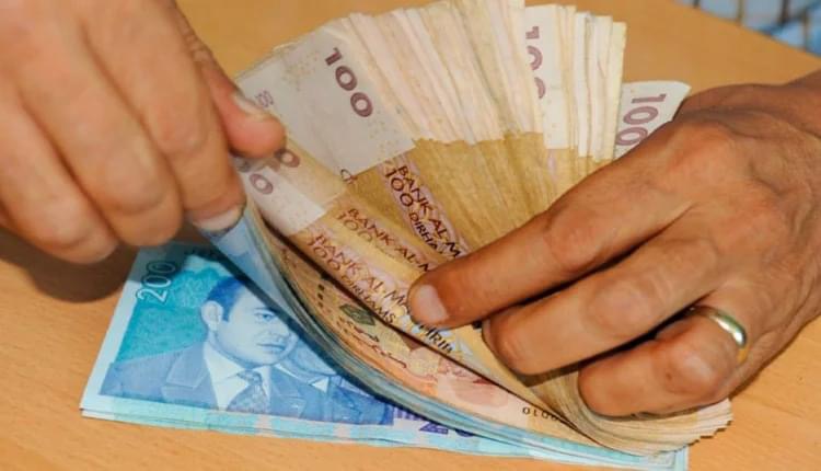 شخص يمسك رزمة من النقود المغربية
